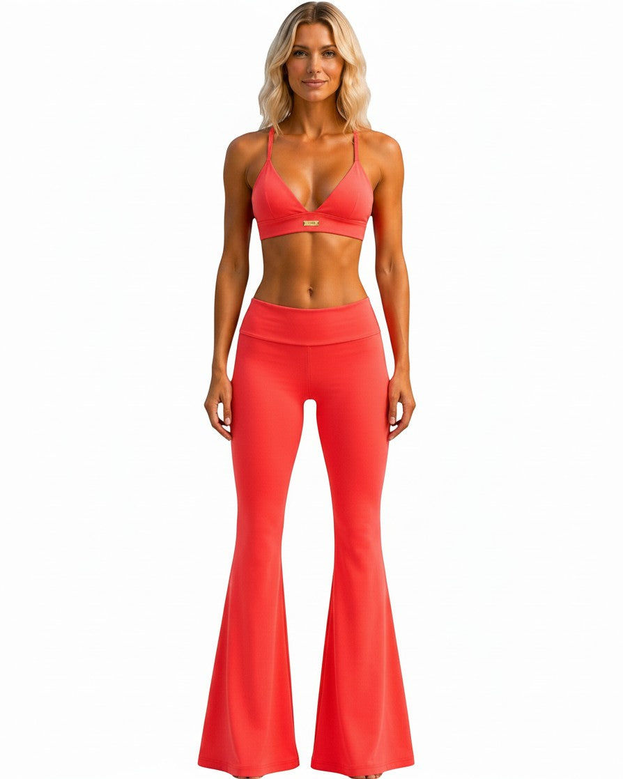 Phural She Did It Anyway high-waisted coral flare leggings worn by a model with a matching sports bra